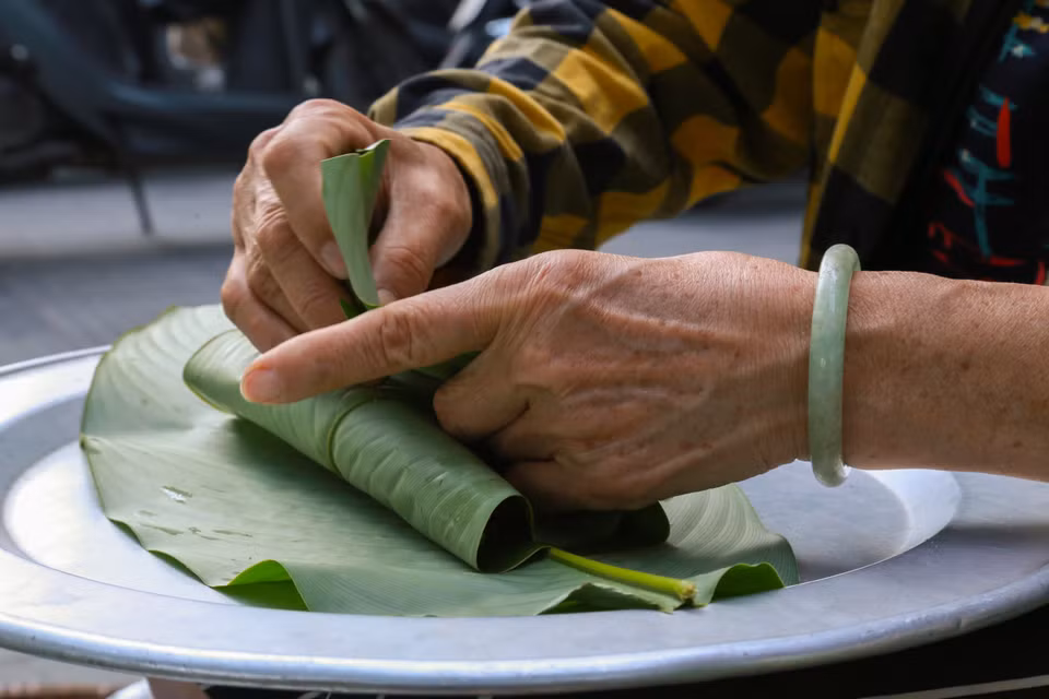 Los granos de arroz verde se envuelven meticulosamente en hojas de loto y se atan con tiras antes de ser entregados al comprador. Foto: Quynh Anh/VNA
