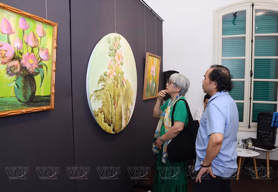 Invitados visitan y disfrutan de las pinturas de loto. (Fuente:VNA)