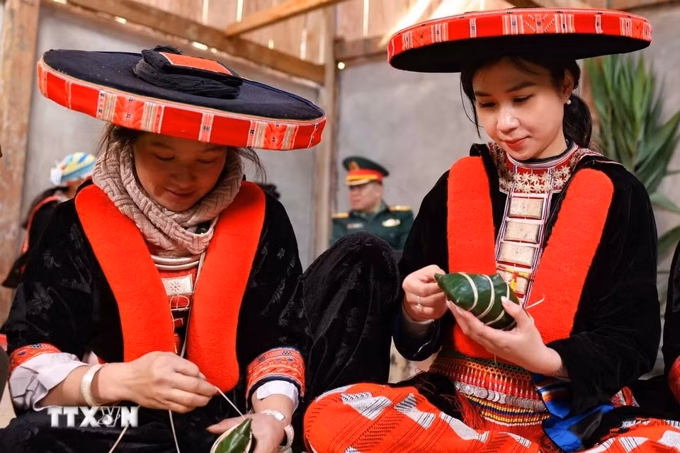 Una turista de Hanoi, vestida con ropa tradicional de los Dao rojo, participa emocionada en la elaboración del banh chung gu (la versión noroeste del banh chung). (Foto: VNA)