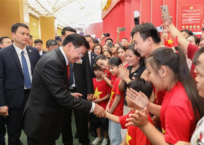 El secretario general del Partido Popular Revolucionario y presidente de Laos, Thongloun Sisoulith, interactúa con niños en el Centro Nacional de Exposiciones en Hanoi. (Fuente: VNA) vna-potal-doan-dai-bieu-cap-cao-lao-va-campuchia-tham-quan-trien-lam-thanh-tuu-dat-nuoc-8252478.jpg