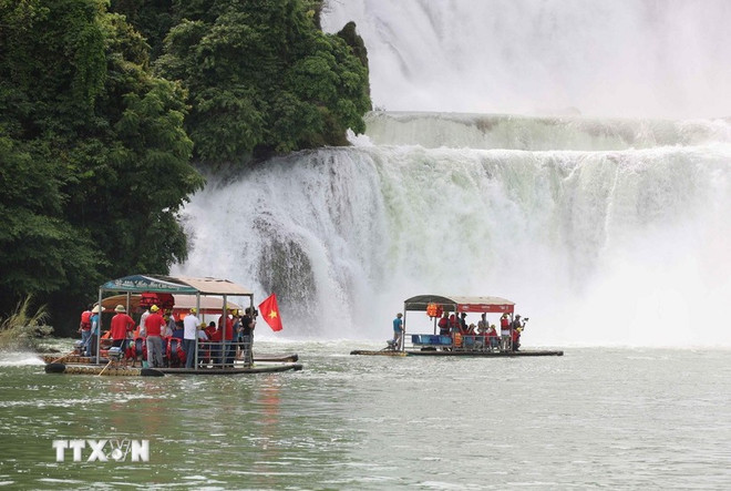 Turistas vietnamitas con banderas nacionales visitan la zona de cooperación turística transfronteriza entre la cascada Ban Gioc (Vietnam) y Detian (China). (Foto:VNA) du-lich-vn-trung-quoc.jpg
