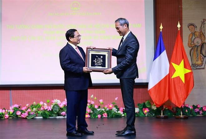 El primer ministro Pham Minh Chinh entrega obsequios a representantes de la comunidad vietnamita en Francia. (Foto: VNA) vna-potal-thu-tuong-va-phu-nhan-gap-go-can-bo-nhan-vien-dai-su-quan-va-cong-dong-nguoi-viet-nam-tai-phap-8084661.jpg