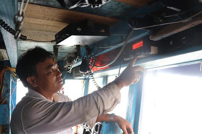 Los pescadores de Phu Yen revisan el sistema de monitoreo de viaje antes de salir al mar. (Foto: VNA) vna-potal-phu-yen-di-tung-ngo-go-tung-nha-van-dong-ngu-dan-chong-khai-thac-iuu-8047627.jpg