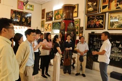 Visitantes escuchan la presentación sobre la historia de la laca en el taller de producción de Dinh Hoa. (Foto: Vietnam+) 