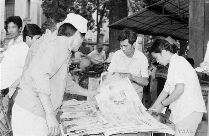 Ciudadanos de Hanoi compran el "Noticiero vespertino" de la VNA para seguir las noticias de la clausura del VII Congreso Nacional del Partido (17 de julio de 1991). Foto: Huu Oai - VNA