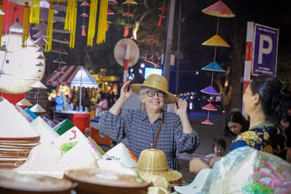 Una visitante internacional queda encantada con los productos tradicionales vietnamitas en el Festival de Regalos Turísticos de Hanoi 2025. (Fuente: VNA)