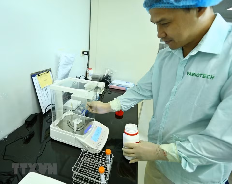 Expertos usan un medidor para fabricar la vacuna. La selección de vacunas se evalúa y ajusta continuamente durante el proceso de prueba. (Foto: VNA)