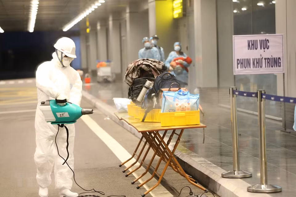 Pulverización de productos químicos para desinfectar el equipaje de los viajeros que regresaron de Wuhan (China). (Foto: VNA)