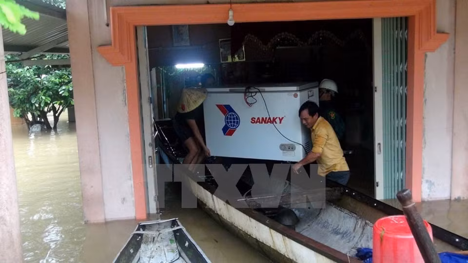 Las personas ayudan a una familia local a evacuar activos en un área inundada en la provincia de Quang Tri (Foto: VNA) 