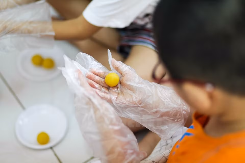 Un niño forma la guarnición – hecha de frijol verde cocido a vapor – en bola. (Fuente: VNA)