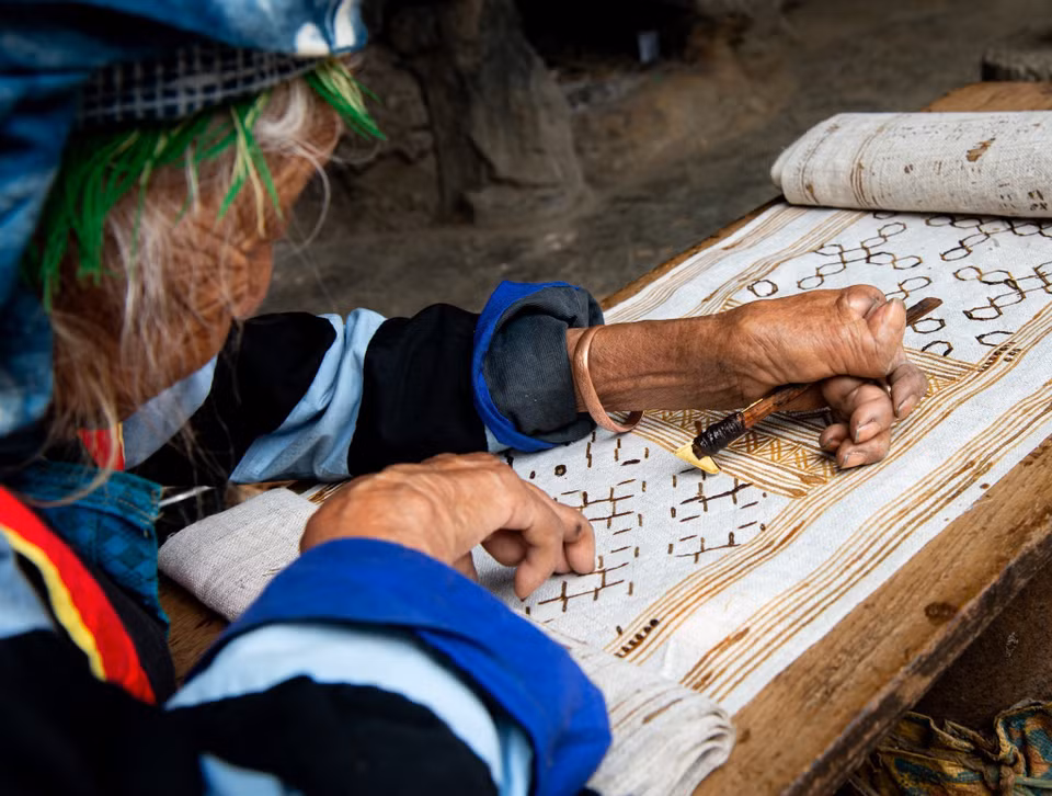 Mujeres de la étnia Mong pintan con cera de abejas sobre lino. (Foto: VNA)