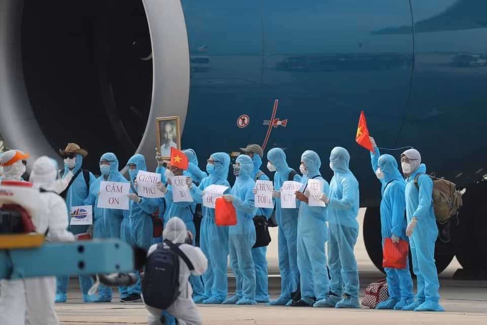 Los reporteros cubren la bienvenida a un vuelo especial que trae a ciudadanos vietnamitas a casa desde Guinea Ecuatorial, quienes aterrizaron de manera segura en el aeropuerto de Noi Bai (en Hanoi), en medio del complicado desarrollo de la pandemia de la COVID-19 en el mundo. (Foto: Thanh Dat/VNA)