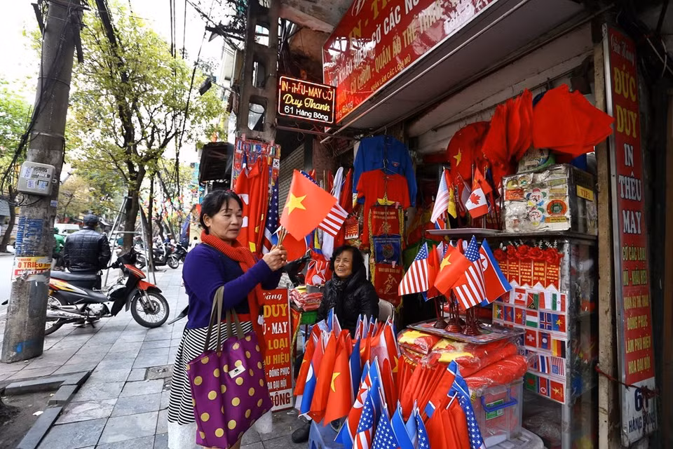 Los turistas compran banderas de EE.UU., Corea del Norte y Vietnam en la calle Hang Bong, Hanoi. (Foto: VNA)