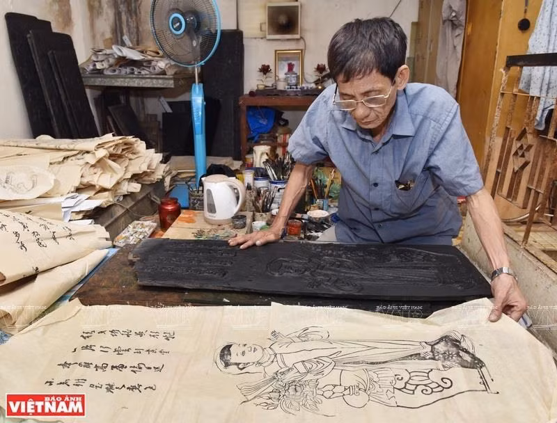 Le Dinh Nghien comienza con bloques de madera para imprimir formas básicas de las pinturas y luego dibuja los detalles. (Foto: VNA)