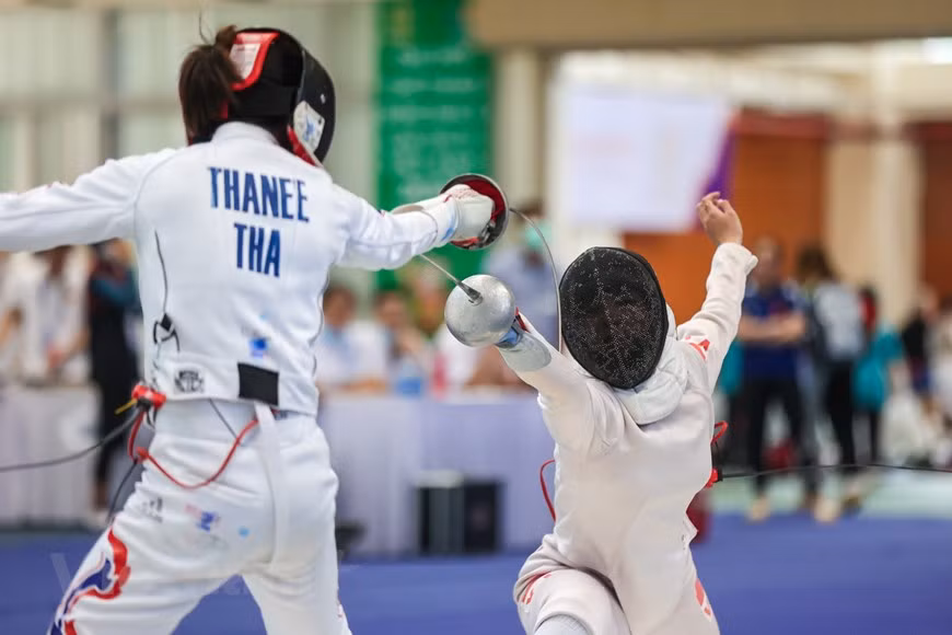 Una escena del combate de la joven atleta Nguyen Phuong Kim enfrentando a su oponente Thanee Korawan de Tailandia. En la esgrima moderna se usan tres armas: el florete, la espada, y el sable, hechas de acero templado. La longitud mínima permitida de la hoja para florete y espada es de 90 cm y en el caso del sable de 88 cm, siendo la longitud máxima del arma de 110 cm para las dos primeras y de 105 cm para el sable. El peso máximo autorizado debe de ser inferior a 500 g en el florete y sable y de 750 g en la espada. La meta de la selección vietnamita de esgrima en los SEA Games 31 es ganar de dos a tres medallas de oro. (Foto: Vietnam+)