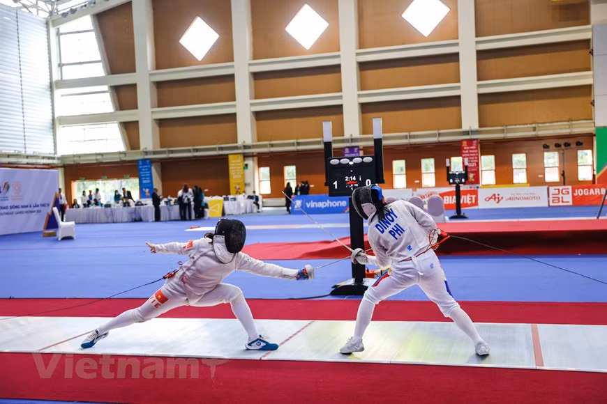 Gracias a una excelente técnica, la esgrimista Vu Thi Hong ganó contra su oponente Dinoy Ivy Clair en un partido en los XXXI Juegos Deportivos del Sudeste Asiático (SEA Games 31). La esgrima, conocida también como esgrima deportiva para diferenciarla de la histórica, es un deporte de combate en el que se enfrentan dos contrincantes debidamente protegidos que deben intentar tocarse con un arma blanca, en función de la cual se diferencian tres modalidades: sable, espada y florete. En los SEA Games 31, más de 13 mil atletas, entrenadores y personal asociado, participan en el evento deportivo; entre ellos, mil 341 son vietnamitas. Se trata de la segunda ocasión que Vietnam organiza los SEA Games, luego de la edición de 2003. (Foto:Vietnam+)