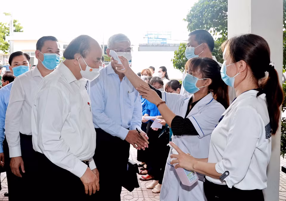 El presidente Nguyen Xuan Phuc mide la temperatura corporal en el encuentro con los votantes en la comuna de Trung Chanh, distrito de Hoc Mon. Fuente: VNA
