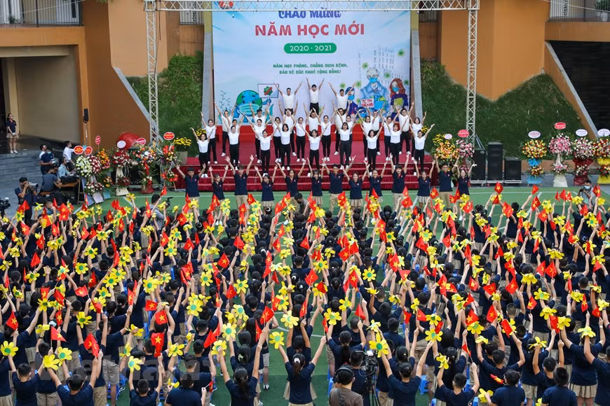 El Departamento de Educación y Capacitación de Hanoi ha exigido que las escuelas locales celebren ceremonias de apertura breves y solemnes para el nuevo año escolar para crear una atmósfera de júbilo para los estudiantes y garantizar la observancia de las medidas de control de la epidemia. Según el documento 2703 / SGDDT-VP del departamento, la ceremonia de apertura del año académico 2020-2021 debe llevarse a cabo en todas las escuelas de la ciudad en forma presencial el 5 de septiembre. Se instruye a las escuelas para que decidan el número de estudiantes que asistirán a la ceremonia en el patio de la escuela en función de su infraestructura para garantizar el distanciamiento físico. Otros estudiantes participan en el evento desde sus aulas. No se realiza ningún ensayo de ceremonia o desfile de nuevos estudiantes. (Fuente:Vietnamplus)