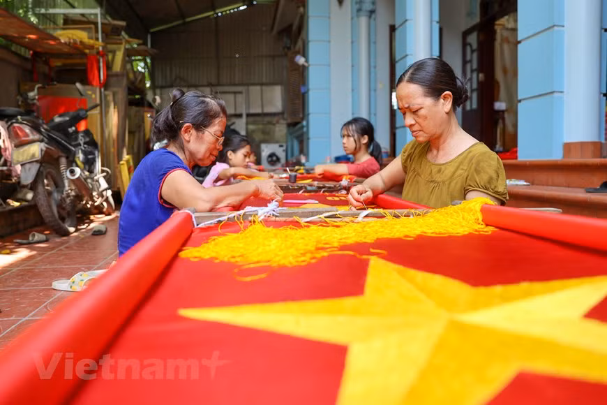 A lo largo de más de una década, la demanda de banderas nacionales ha aumentado notablemente, lo que genera más trabajos para la familia de Vuong Thi Nhung. Para completar una bandera bordada a mano, Nhung tarda de tres a cinco días, mientras que los artesanos menos profesionales pueden demorarse hasta una semana. Las puntadas deben alcanzar un alto nivel de precisión ya que las banderas se emplean en ocasiones formales. Por tal motivo, el costo de un producto hecho a mano es de aproximadamente 13 a 22 dólares según su tamaño, lo que supera muchas veces el precio de una bandera cosida a máquina. (Foto: Vietnam+)