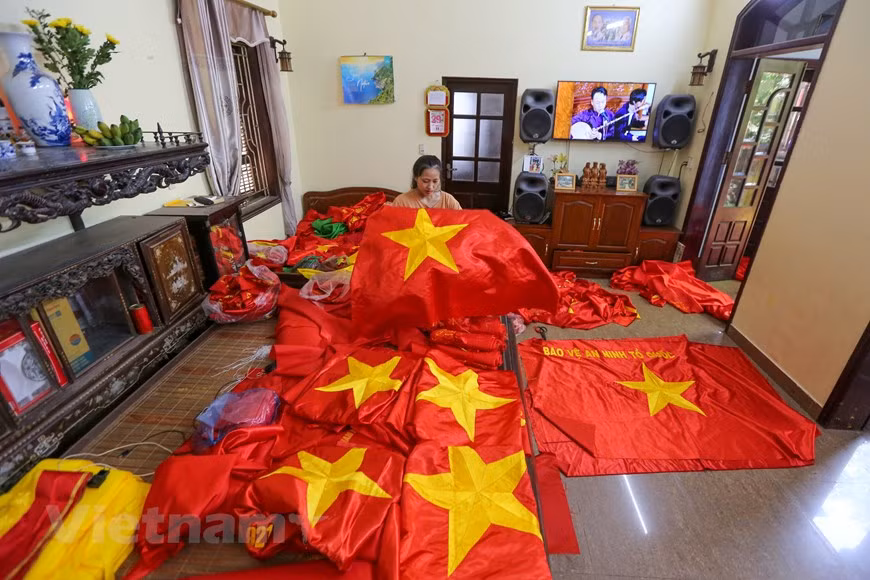 Vuong Thi Nhung dijo orgullosamente que su hija, de 23 años de edad, tiene más de 11 años de experiencia en el bordado de banderas. Se trata de la tercera generación de la familia que estudia este oficio tradicional. A pesar de muchos desafíos, los pobladores de la aldea de Tu Van aún mantienen su trabajo de bordar y coser las banderas nacionales para abastecer a nivel nacional e internacional. En ocasión del Día Nacional de Vietnam (2 de septiembre), la familia de Nhung trabaja continuamente para producir y entregar los pedidos a la calle de Hang Bong, un destino con larga tradición de venta de este producto. (Foto: Vietnam+)