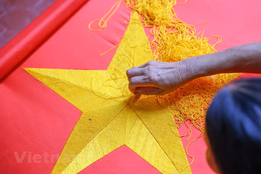 Al explicar la razón por la que no emplea las máquinas, Vuong Thi Nhung comentó que quería conservar las tradiciones del oficio que heredó de sus ancestros. Para coser una hermosa bandera es necesario contar con las etapas de confeccionar las telas, luego de medir, cortar, insertar la estrella y coser, por lo que se requiere de un alto nivel de habilidad y meticulosidad del artesano en cada puntada. Para poder producir una bandera hecha a mano, el paso más importante es seleccionar una tela de calidad, que debe proceder de la aldea de La Khe, en el distrito de Ha Dong, en Hanoi. (Foto: Vietnam+)