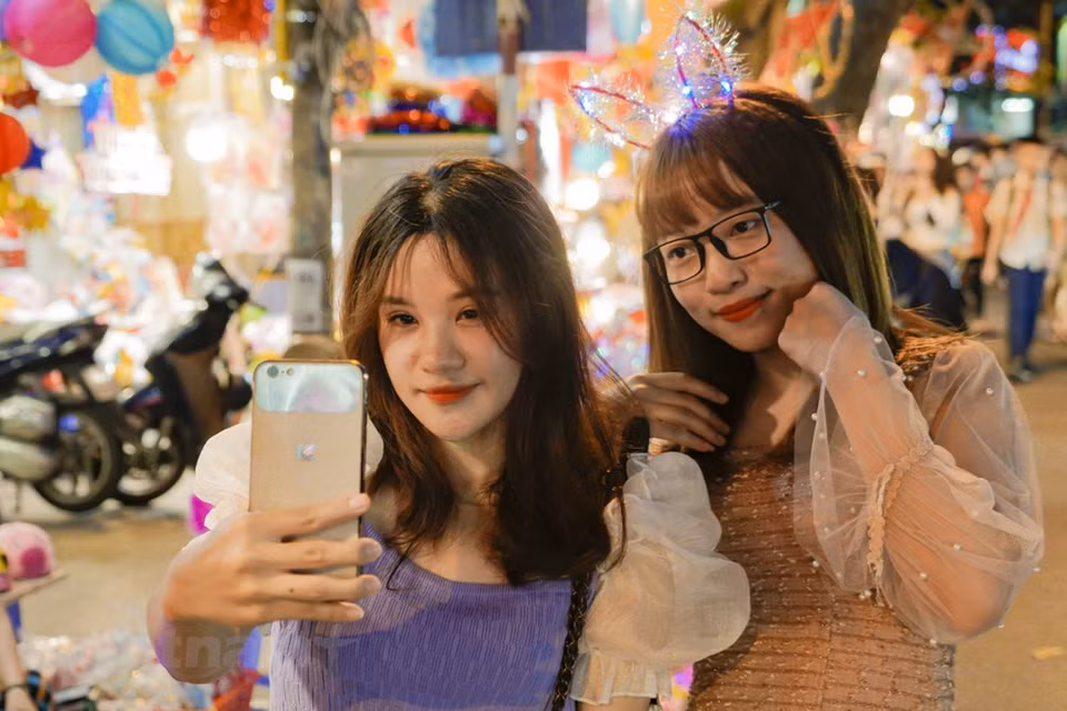 Una pareja joven saca fotos en la calle con linternas coloradas. (Foto: Minh Hieu / Vietnam +)
