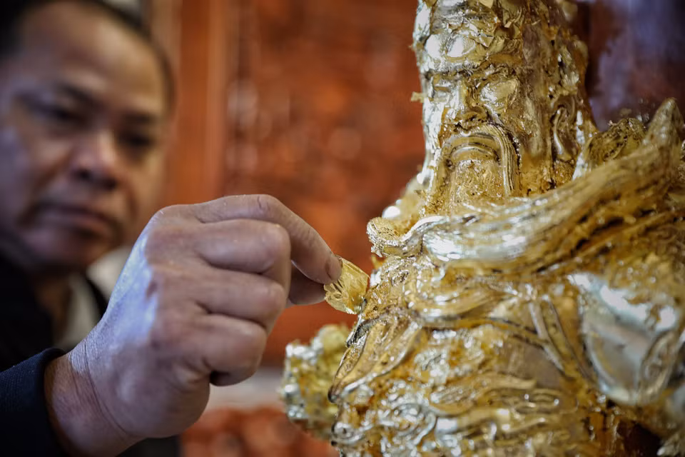 El artista Nguyen Anh Chung coloca oro en una estatua. (Foto: VNA)