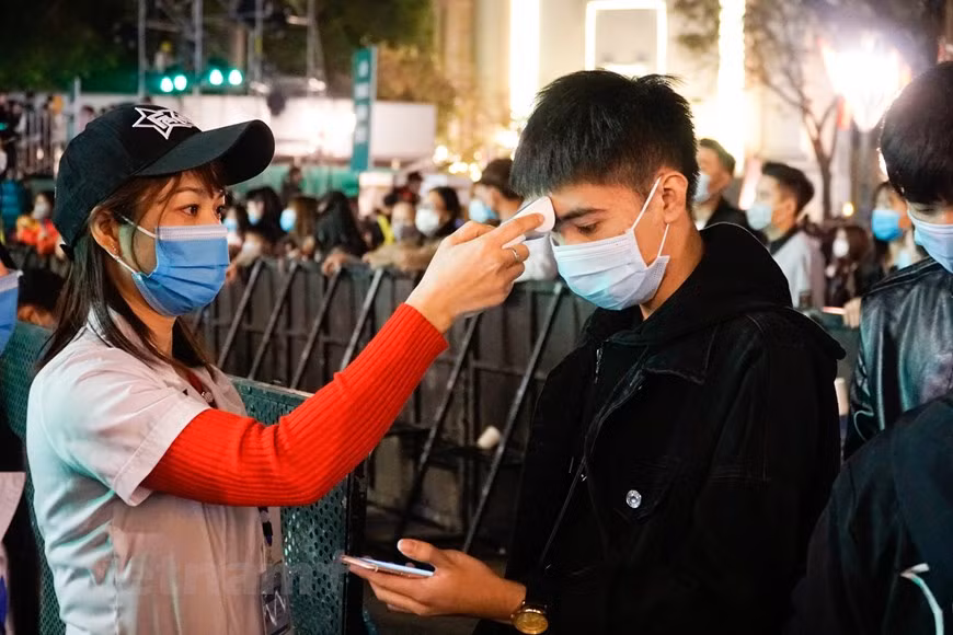 Una funcionaria médica mide la temperatura corporal de un espectador. (Fuente: VNA)