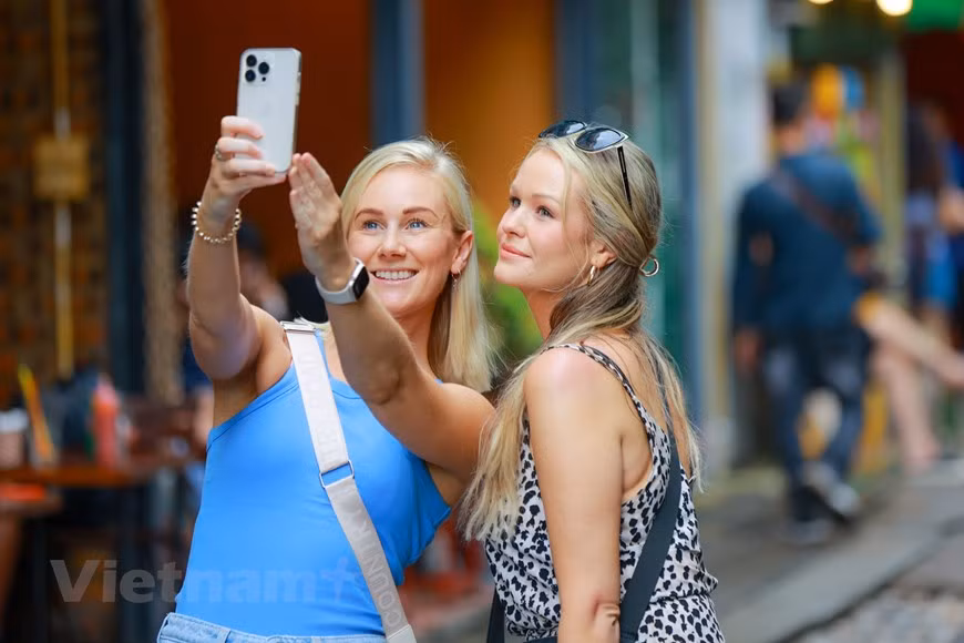 Mujeres turistas toman fotos libremente en las calles de Hanoi sin temor a condiciones inseguras. (Foto: Vietnam+)