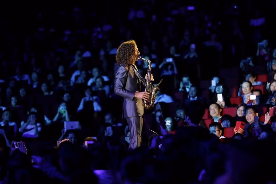 Kenny G aparece en medio de la audiencia, con el célebre saxófono.