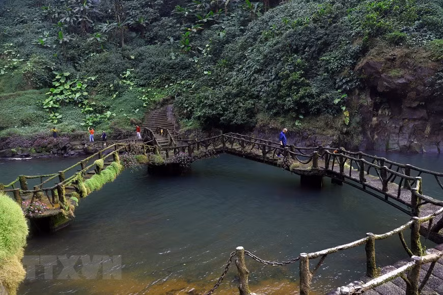 Un pequeño puente conecta las dos orillas al pie de la cascada, cubiertas durante todo el año de musgo. (Foto: VNA)
