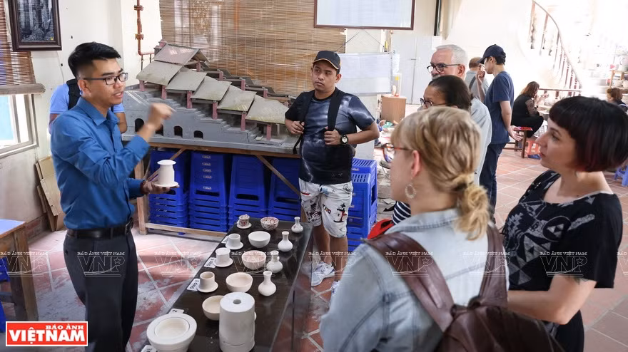 Visitantes extranjeros aprenden con un guía sobre la cultura e historia de la aldea de oficio tradicional de cerámica de Bat Trang. (Fuente: VNA)