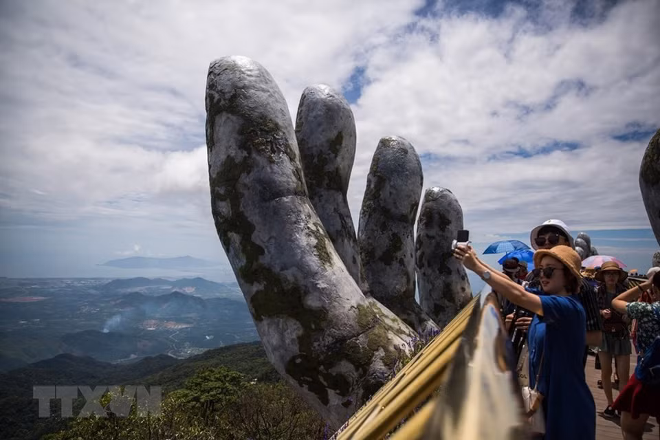 Los visitantes admiran magnífico escenario natural al estar de pie en el Puente Vang. (Fuente: VNA)