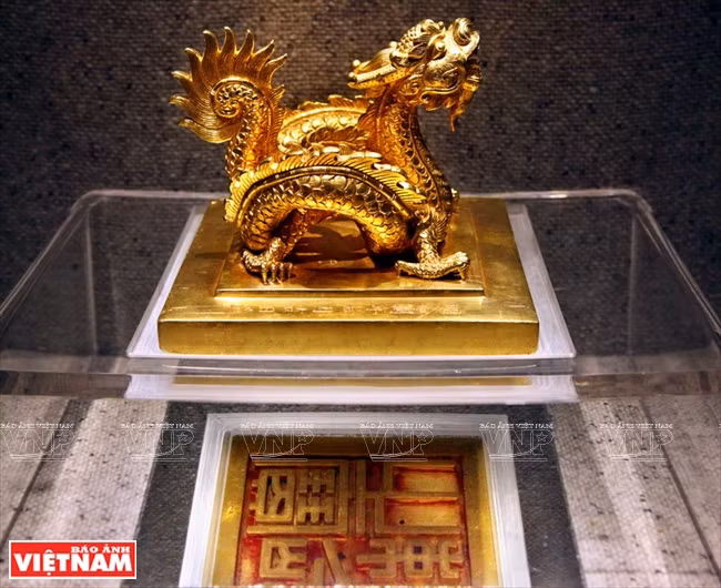 El sello de oro "Sac menh chi bao" pesa 8,3 kg, que fue lanzado en 1827 bajo el reinado del rey Minh Mang. Su perilla se hace en forma de un dragón que rueda y su cara se moldea con las cuatro palabras "Sac menh chi bao" en relieve. El sello se utilizó para la promoción de rango de los funcionarios civiles y militares, así como la concesión del título de las deidades y los seres humanos. Esta es la única exposición, que simboliza el poder de la dinastía Nguyen, con un valor especial en la colección de tesoros de oro de la dinastía Nguyen. Foto: Cong Dat / VNP