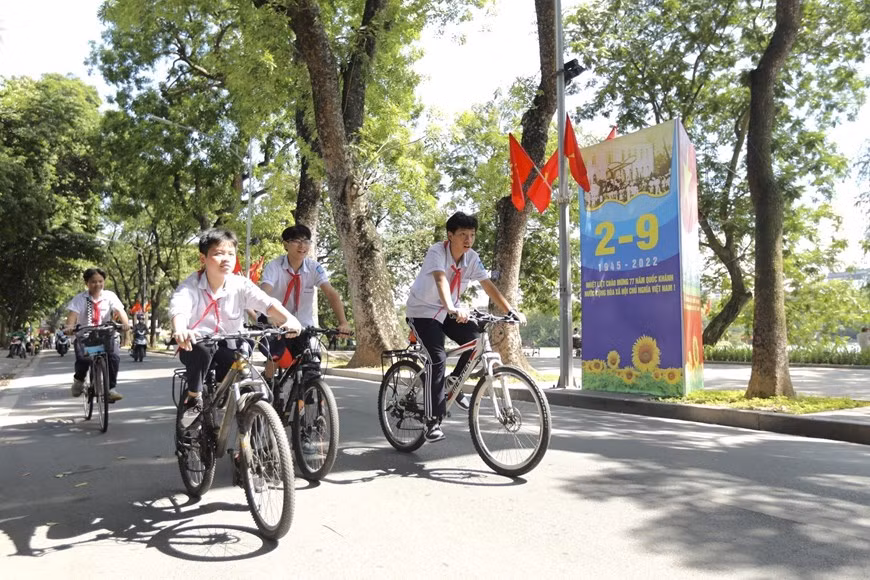 Los alumnos pasan junto a un letrero a orillas del lago Hoan Kiem. (Foto: VNA)
