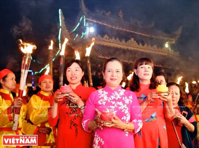 La bailarina de “Hau dong” Tran Thi Kim Hue (vestida ao dai rosa) durante la procesión de antorchas (Fuente: VNA)