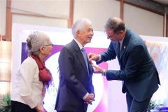 El embajador de Francia en Vietnam, Olivier Brochet, entrega la Orden Nacional de la Legión de Honor al profesor Jean Tran Thanh Van durante la ceremonia. (Foto: VNA)