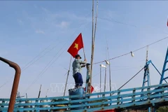Pescadores izan la bandera de la Patria antes de zarpar para reafirmar la soberanía sobre las islas y mares de la Patria. (Foto: VNA)