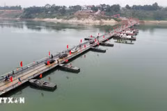 Personas y vehículos circulan con normalidad a través del puente flotante sobre el río Lo en la mañana del 16 de febrero. (Foto: VNA)