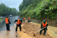 Guardias fronterizos de la ciudad de Hue excavan tierra y rocas para nivelar la carretera afectada por el deslizamiento de tierra en el Paso de Pe Ke, comuna de A Luoi 1. (Foto: VNA)