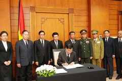El secretario general del Partido Popular Revolucionario de Laos y presidente del país, Thongloun Sisoulith, escribe en el libro de condolencias. (Fuente: VNA)