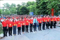 Delegados, jóvenes y sindicalistas realizan la ceremonia de izamiento de la bandera. (Foto: VNA)