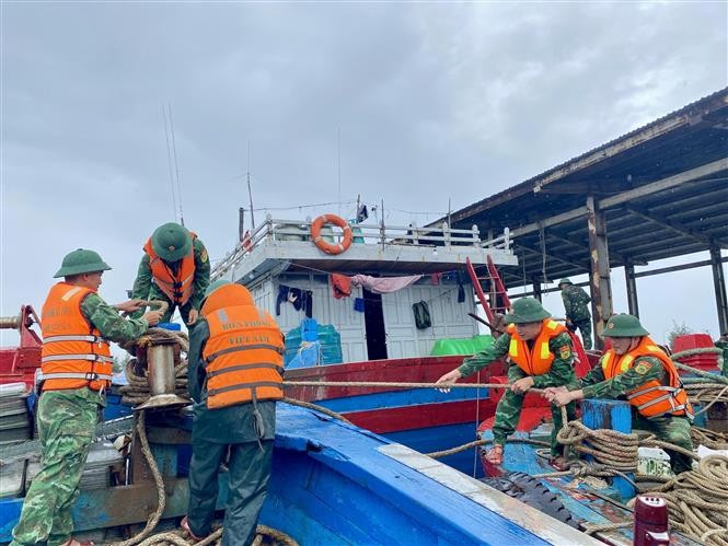 Las autoridades ayudan a los pescadores a amarrar los barcos (Foto: VNA)