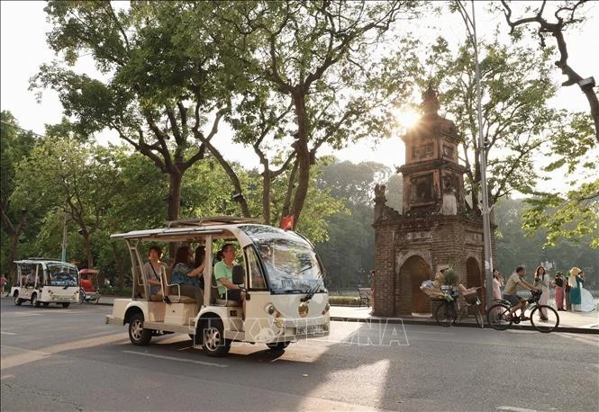 Turistas recorren el lago Hoan Kiem en coches eléctricos. (Foto: VNA)