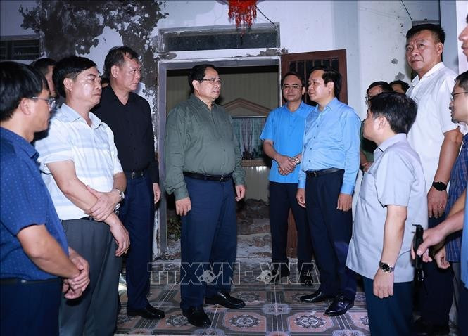 El primer ministro Pham Minh Chinh (centro) visita la comuna de Quy Nhat para inspeccionar y dirigir las labores de recuperación tras el tifón Bualoi. (Foto: VNA)