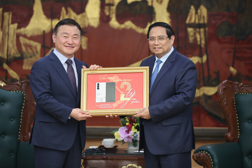 El primer ministro Pham Minh Chinh (derecha) entrega una placa conmemorativa de la producción del teléfono móvil número dos mil millones de Samsung en Vietnam a Roh Tae Moon (Foto: baochinhphu.vn)