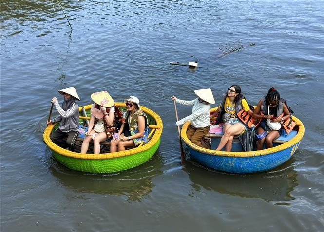 Turistas foráneos disfrutan de un paseo en bote cesta en el bosque de cocoteros local. (Foto: VNA)