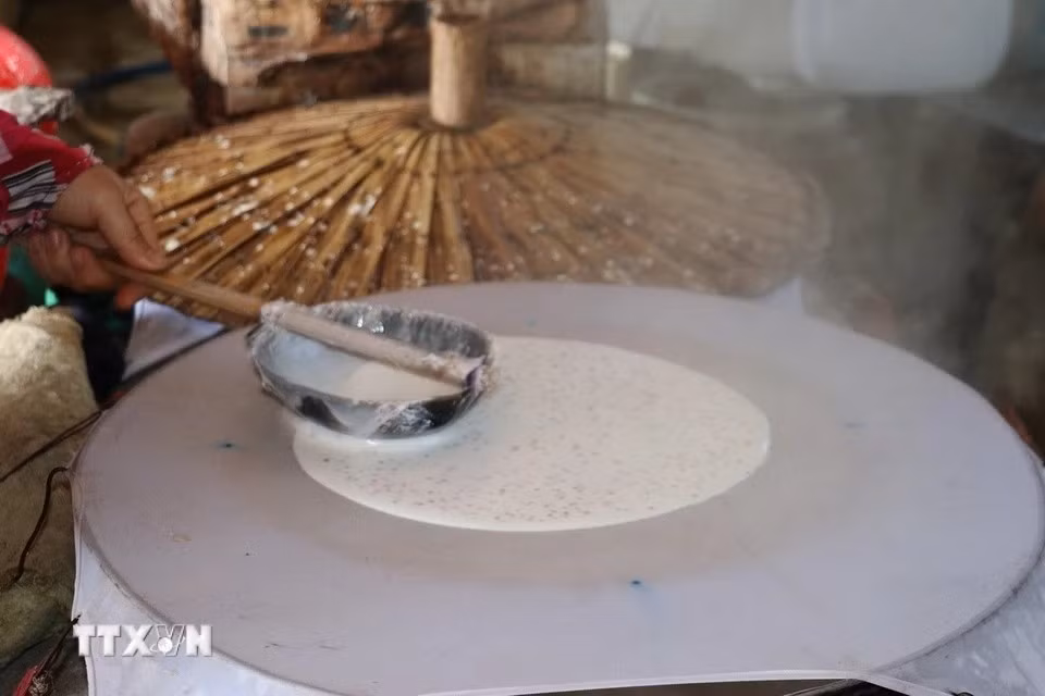 El paso de recubrimiento de la mezcla hecha de harina de arroz, sésamo y leche de coco debe realizarse de manera rápida y uniforme para garantizar que el panqueque tenga el grosor adecuado. (Foto: VNA)