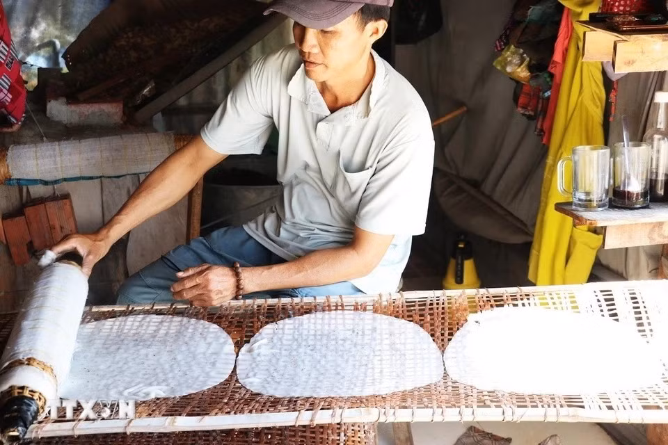 Nguyen Van Tai, de la aldea de Hau Thuan, comuna de Hau Thanh, coloca los panqueques de arroz recién cocinados en una estela para secarlo. (Foto: VNA)