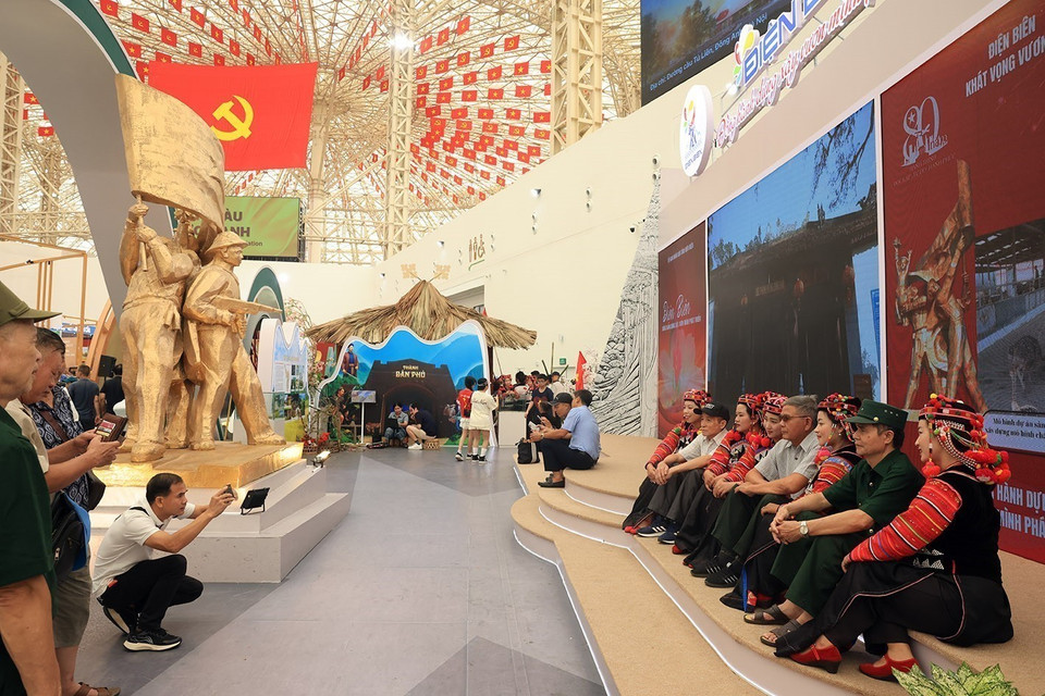 Visitantes se toman fotos de recuerdo con los pobladores de la etnia Ha Nhi en el área de exhibición de la provincia de Dien Bien. (Foto: VNA)